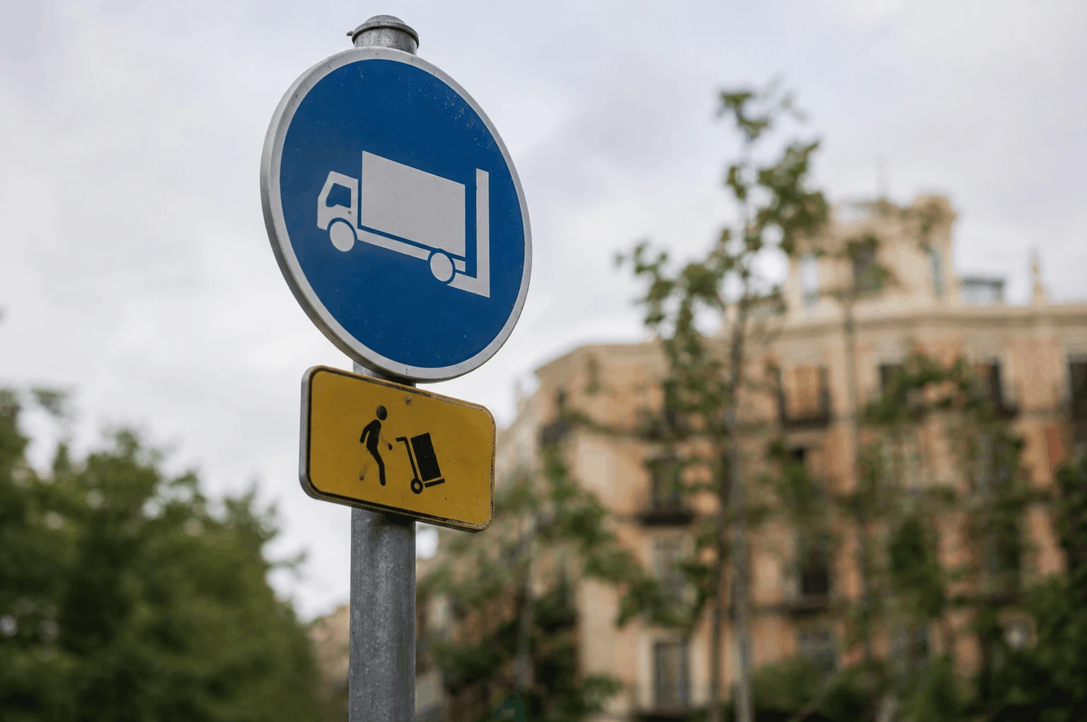 TREINTA MINUTOS Y UN PISO ENTERO. CARGA Y DESCARGA EN LOS EJES VERDES DEL EIXAMPLE 4 SEÑAL VERTICAL DE ZONA DUM CON EL CÓDIGO DE ÁREA Y LA PLACA DE HORARIOS EN UNA CALLE PACIFICADA DEL EIXAMPLE DE BARCELONA